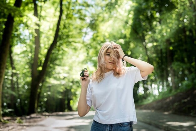 Close-up shot of a person wearing Soundcore Liberty 3 Pro wireless earbuds while jogging in a park, with the earbuds highlighted against a blurred background of trees and sunlight.
