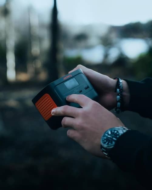 A person holding a small, compact portable projector in their hand, emphasizing its size and portability. The background is a blurred outdoor setting, suggesting on-the-go use.